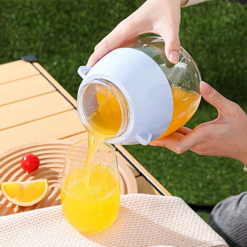 Blender Bottle - Hands pouring orange juice from a light blue container into a glass, with an orange slice and cherry on the surface beneath