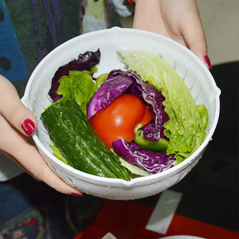 Serving Bowl Set - Hands holding a white slotted bowl filled with whole fresh cucumber, tomato, lettuce, and purple cabbage, with water droplets on the bowl.