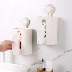 Tissue Box Holder - Two white suction-mounted storage units installed on a white marble tile bathroom wall, with a hand pulling a tissue from the lower unit near a sink and toothbrush holder