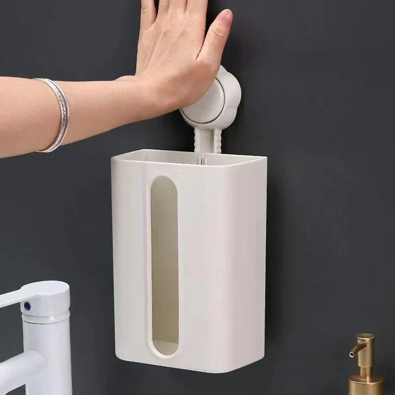 Tissue Box Holder - A hand pressing the suction mount of an empty white wall-mounted tissue holder against a dark wall, near sink fixtures