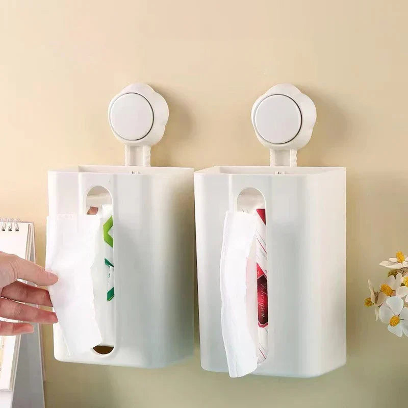 Tissue Box Holder - Two white wall-mounted tissue holders side by side on a beige wall, each with a tissue protruding; one is being pulled by a hand