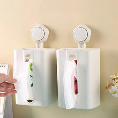 Tissue Box Holder - Two white wall-mounted tissue holders side by side on a beige wall, each with a tissue protruding; one is being pulled by a hand