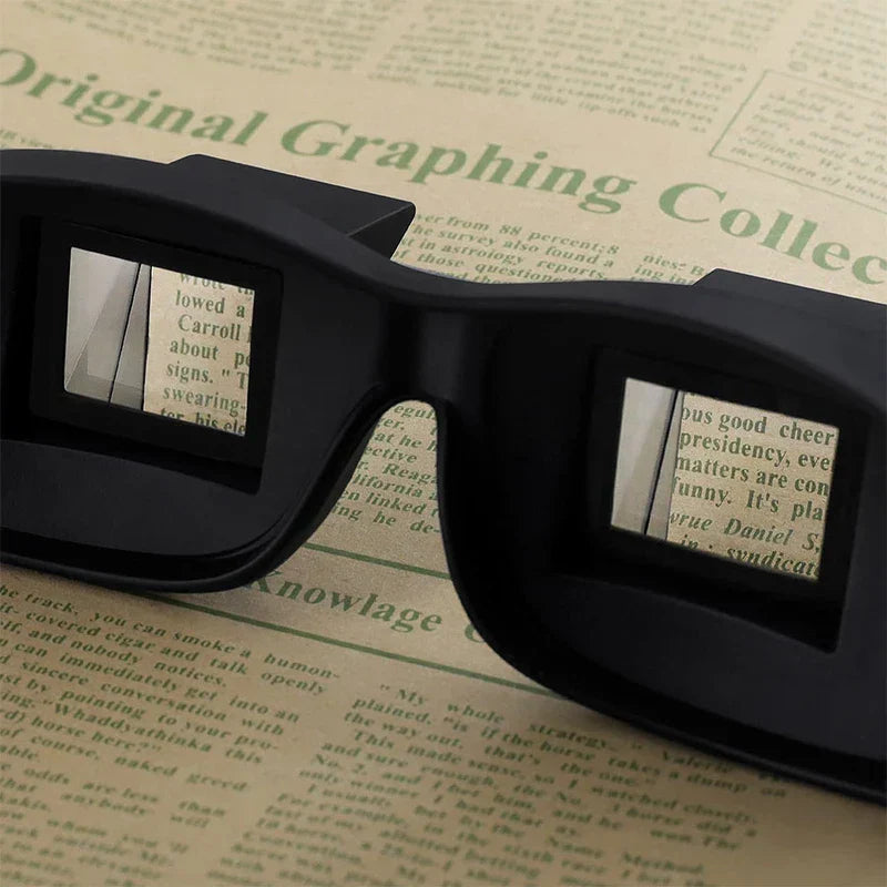 Lazy Periscope Horizontal Reading Glasses - Black prism eyeglasses resting on printed paper, showing mirrored reflected text through their lenses.