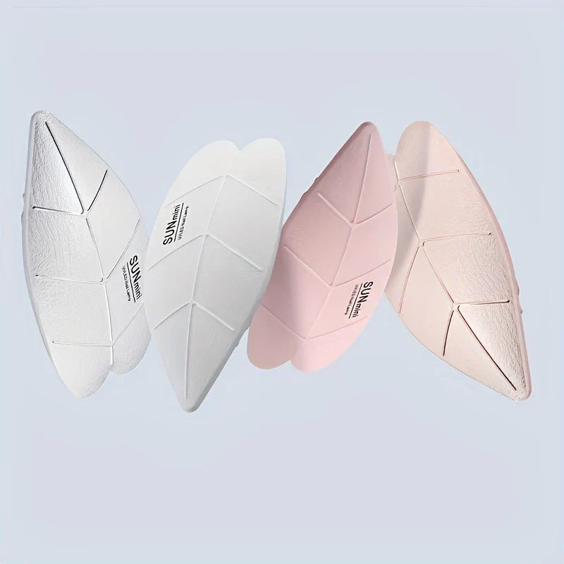 Lamp Uv Led Nail - Vier blattförmige Mini-Nagellampen in Weiß, Hellgrau, Rosa und Hautfarbe, vor einem hellblauen Hintergrund.