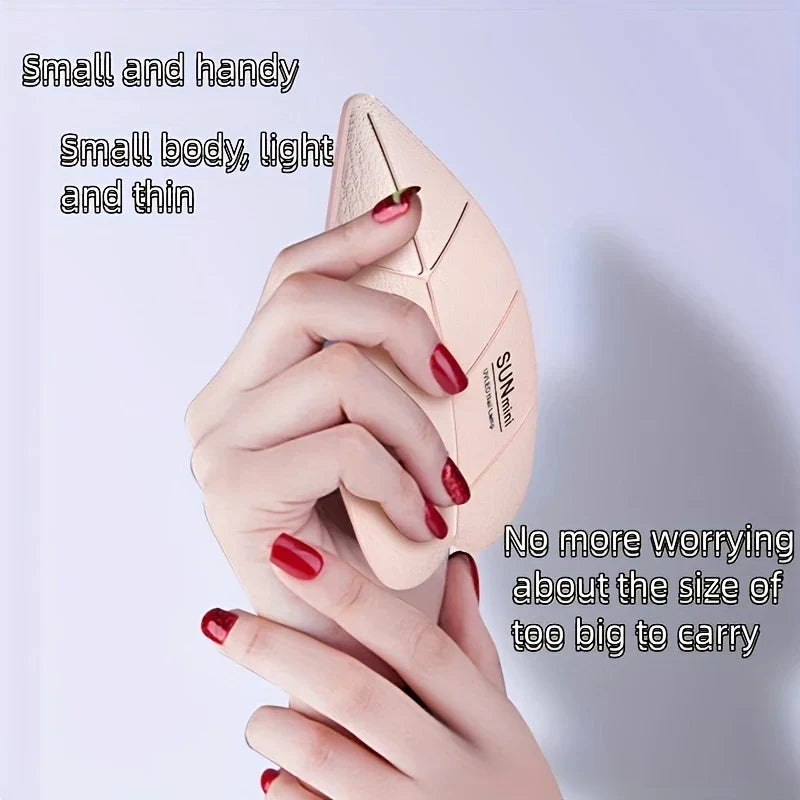 Lamp Uv Led Nail - Hände halten eine hautfarbene blattförmige Mini-Nagellampe, die ihre schlanke Handheld-Größe zeigt.