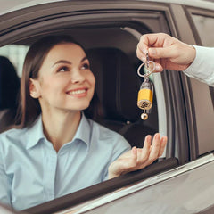 Leather Keychain - Woman in a car receives a gold gear shift keychain from a hand outside the window