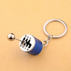 Leather Keychain - Close-up of blue gear shift shaped keychain on a tan background