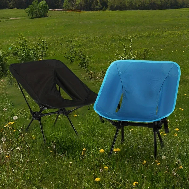 Folding Camping Chair - Black and bright blue chairs set up in a grassy wildflower field