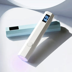 Nail Wand - Two handheld UV light wands (white with lit '60' display and light blue) rest on a smooth white curved surface, with one leaning across the other.