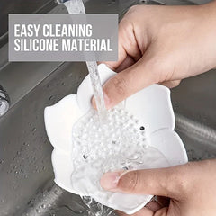 Soap Dish Holder - Two hands rinsing a white flower-shaped object under running water in a sink.