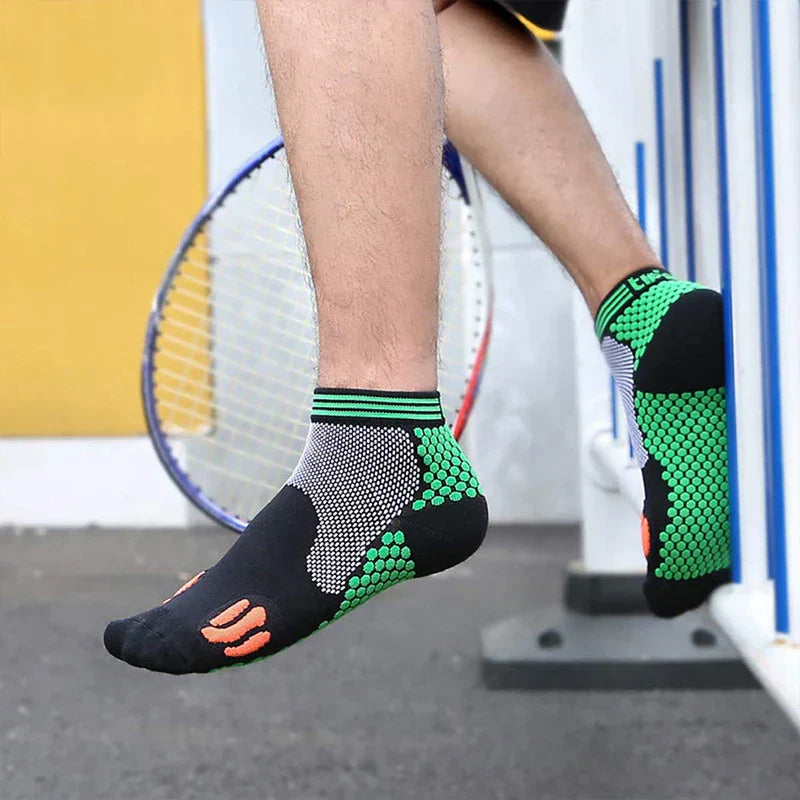 Casual Socks Pack - Close-up of a person’s foot in a short athletic sock, raised near a tennis racket, showing the sock’s textured green side panels