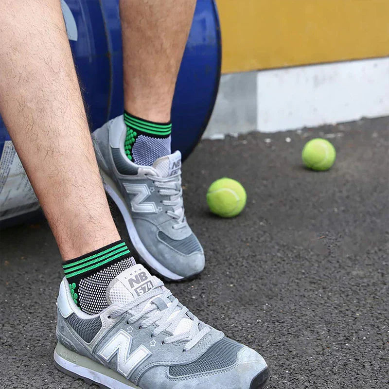 Casual Socks Pack - Person’s lower legs and feet wear gray sneakers with black green-trimmed ankle socks, two tennis balls lie on dark pavement nearby.