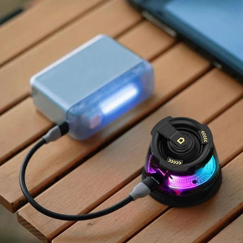 Floating Speaker - Translucent blue power bank connected via cable to a small black speaker with purple and blue LED glow, placed on wooden slatted surface.