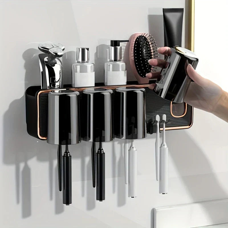 Magnetic Toothbrush Holder Set - Hand lifting one magnetic cup from the wall-mounted holder, with three remaining cups, toothbrush slots, top shelf holding a razor, two pump bottles, a hairbrush, and a toothpaste tube