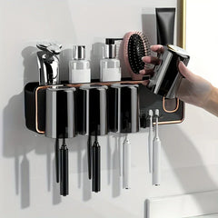Magnetic Toothbrush Holder Set - Hand lifting one magnetic cup from the wall-mounted holder, with three remaining cups, toothbrush slots, top shelf holding a razor, two pump bottles, a hairbrush, and a toothpaste tube