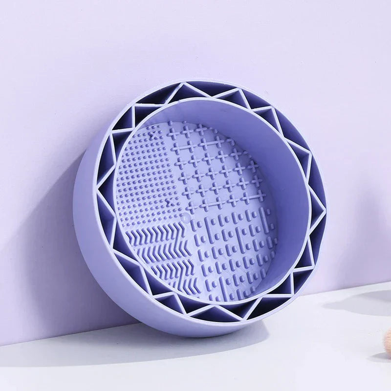 Makeup Brush Cleaning Mat - Close-up of a lavender round silicone bowl with textured interior and triangular outer rim, resting against a light purple background.