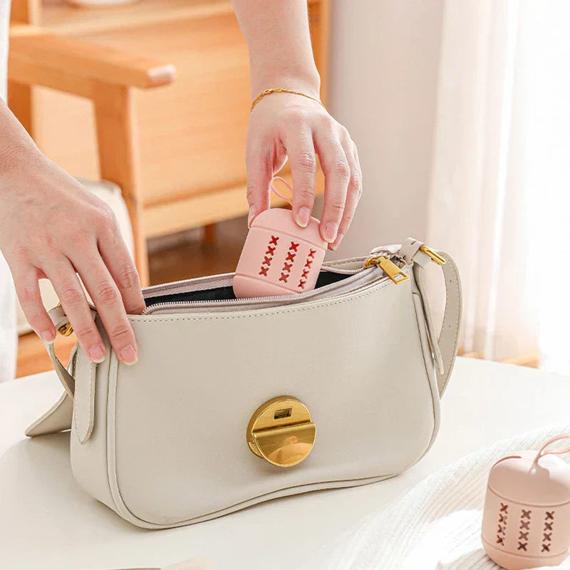 Hands placing a small pink ventilated sponge storage case into a beige shoulder bag for travel