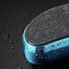 Exfoliador de callosidades: vista parcial en ángulo de un dispositivo azul y negro cubierto de gotas de agua sobre una superficie oscura y húmeda