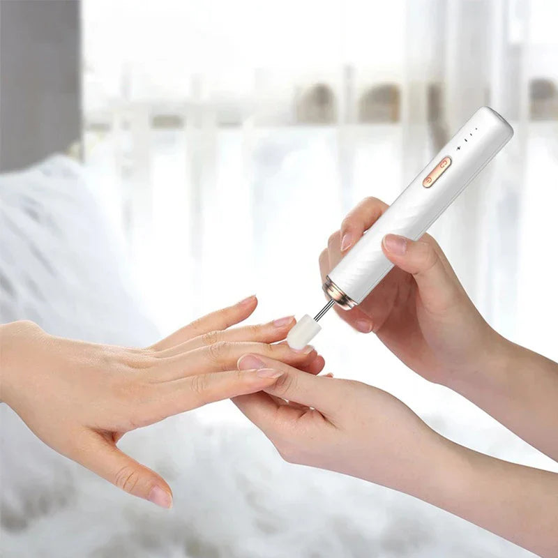 Herramienta de manicura y pedicura: manos sostienen una lima eléctrica blanca con forma de bolígrafo con una punta de lijado blanca, limando la uña de una mano