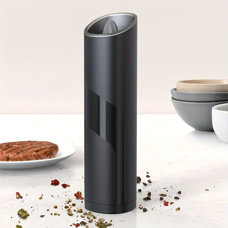 Coffee Bean Grinder - Black grinder standing on a kitchen countertop surrounded by scattered spices, with a cooked patty and stacked bowls nearby