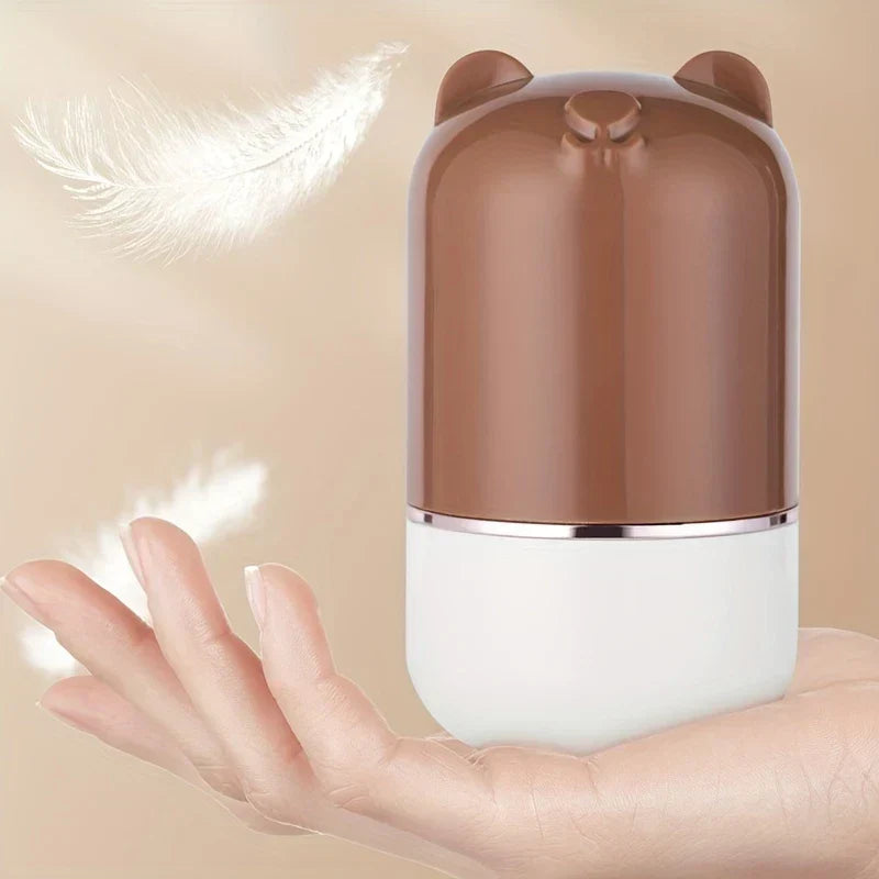 Manual Foot File - The same brown and white bear-eared item resting on an outstretched palm, with floating white feathers beside it.