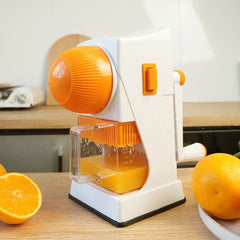 Fruit Juicer - Hand crank juicer sitting on a wood kitchen counter with fresh orange halves and whole oranges nearby, with collected orange juice in the clear cup
