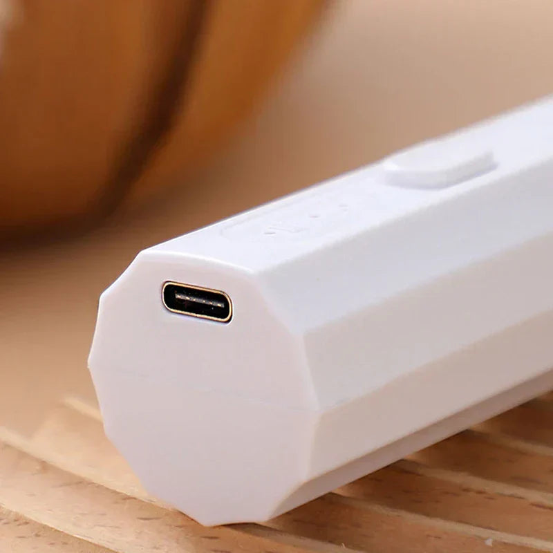 Whisk Mixer - Close-up of the angled USB-C charging end of a white handheld electric device, resting on a slatted wood surface
