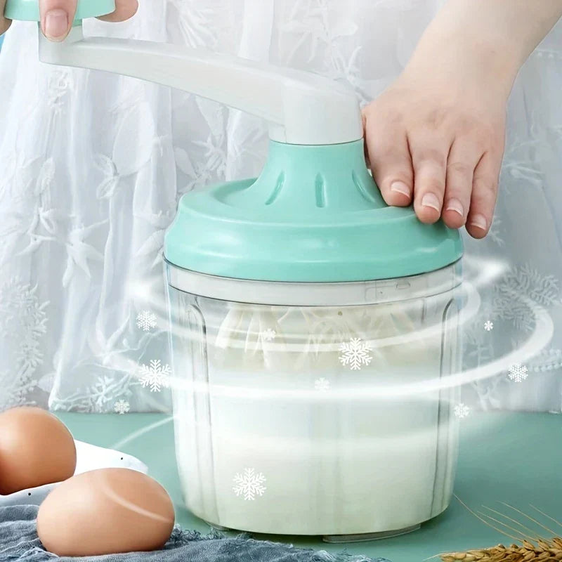 Manual Rotary Hand Whisk Egg Beater - Two hands turning the rotary whisk's crank, with motion effects around the container, eggs placed beside it on the table.