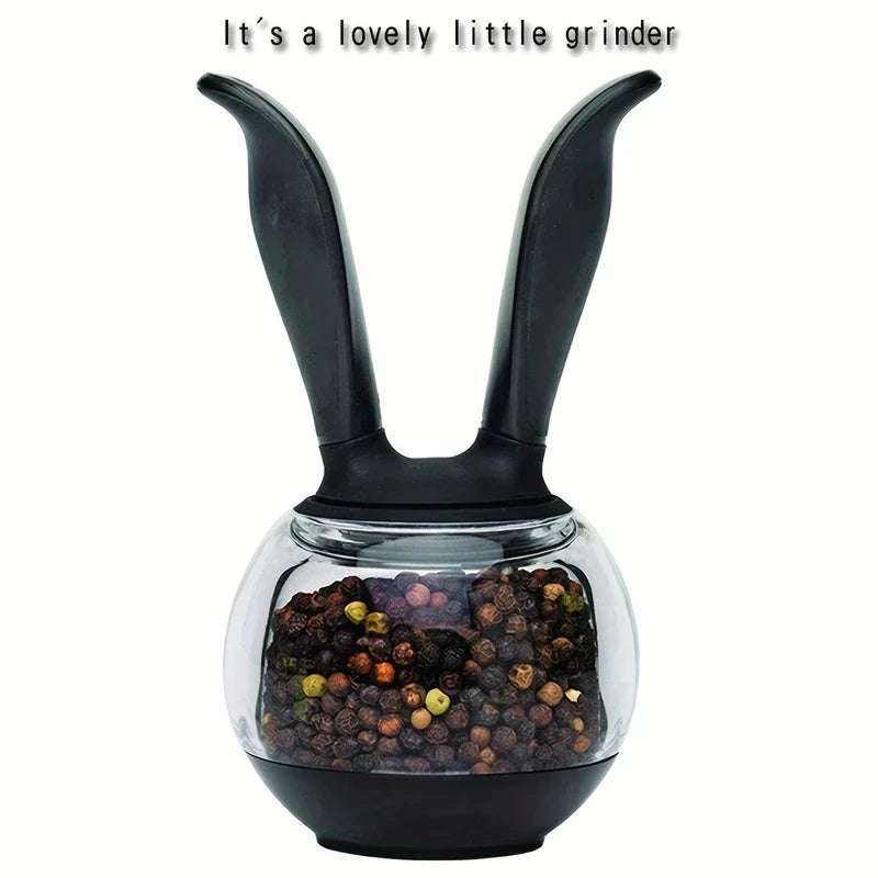 Pepper Grinder - Bunny-shaped manual grinder with black handles, clear body holding mixed peppercorns, text above reads "It's a lovely little grinder".