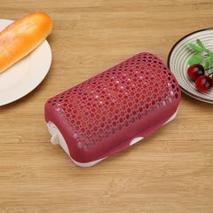 cocedor de salchichas para microondas - Utensilio de cocina perforado en rojo y blanco cerrado sobre una mesa de madera, junto a un panecillo en un plato y un plato de cerezas