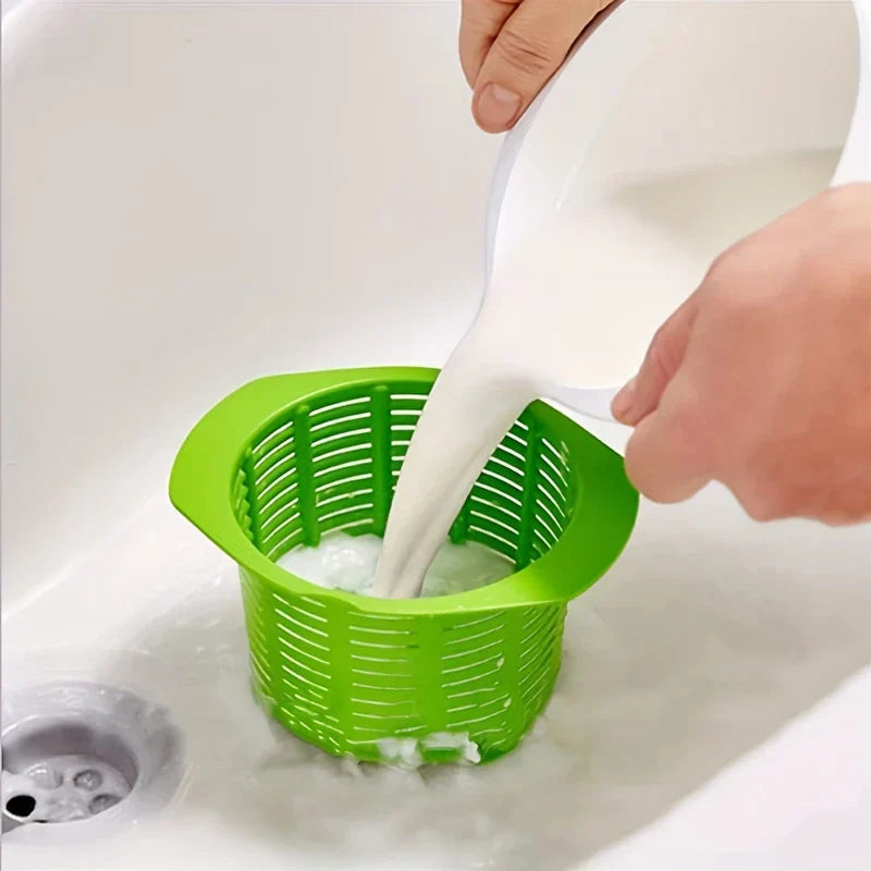 Ricotta Cheese Maker - A person pours white liquid from a pitcher into a green slotted basket set in a white sink, with liquid draining through.