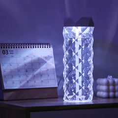 Cool Mist Humidifier - Illuminated transparent diamond-patterned humidifier glowing on desk beside March 2023 calendar in dim lighting