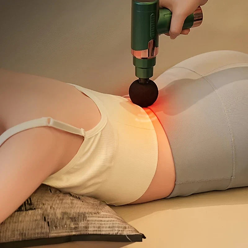 Pistolet de massage par percussion - Personne utilisant l’appareil de massage compact sur le bas du dos, allongée sur une surface rembourrée