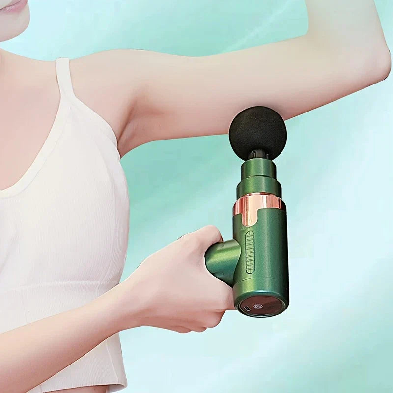 Percussion Massage Gun - A person holding a small green massage gun against their upper arm near the shoulder.