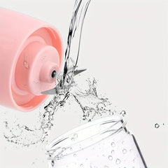 Water rinsing the stainless steel blades of a pink portable blender above a clear glass cup