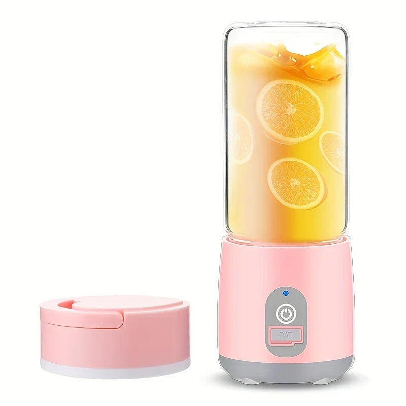 Portable Blender - Portable pink blender with a glass cup containing orange slices and juice, separate pink lid placed to the left.