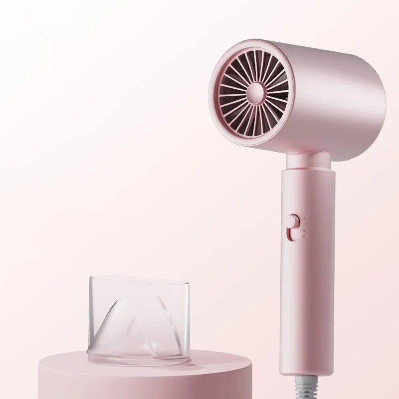 Hair Dryer - Matte pink hairdryer standing upright with a clear concentrator nozzle placed on a pink cylindrical display base