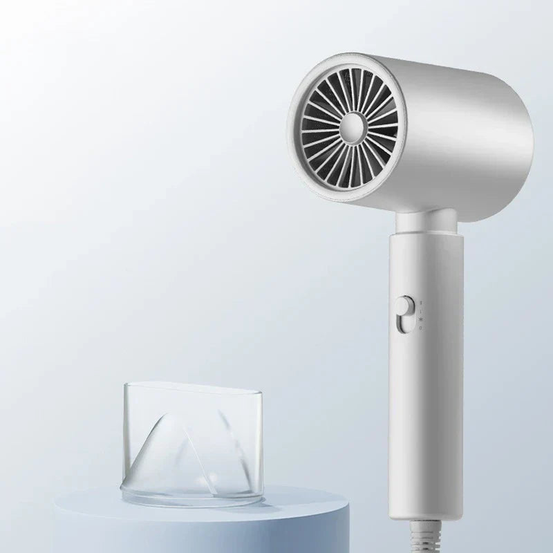 White handheld hair dryer standing upright, with its clear concentrator nozzle placed on a light blue pedestal beside it.