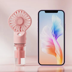 ventilador usb - Ventilador portátil de mano rosa colocado junto a un teléfono inteligente sobre una superficie rosa claro.