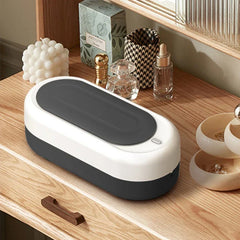 Ultrasonic Jewelry Cleaner - Device placed on a wooden vanity countertop alongside small decor and beauty items