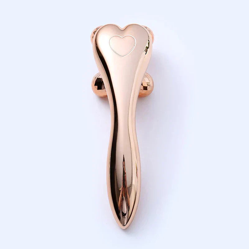 Face Slimming Massager - Rose gold heart-shaped facial roller tool with embossed heart detail, top-down view
