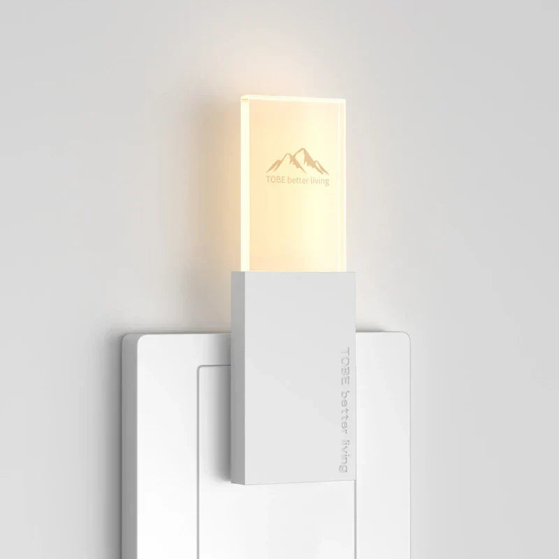 Mosquito Repellent Night Light - White rectangular USB plug-in night light, lit with warm glow, inserted in a white wall socket, viewed against a plain light wall