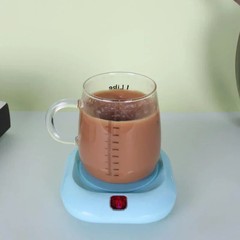 posavasos individual - Taza medidora de vidrio con bebida marrón espumosa sobre un posavasos calefactor azul claro con luz indicadora roja encendida