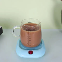 posavasos individual - Taza medidora de vidrio con bebida marrón espumosa sobre un posavasos calefactor azul claro con luz indicadora roja encendida