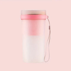 Pink and white juicer blender with a hanging carry strap against a solid light pink background.