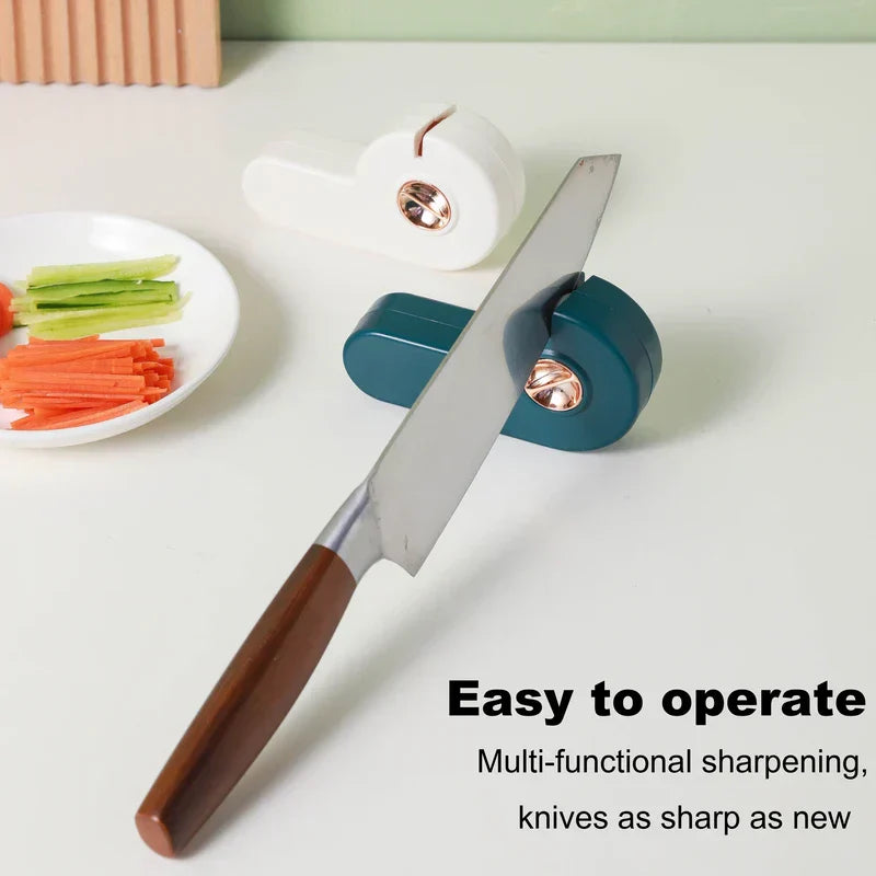 Manual Knife Sharpener - Dark teal sharpening tool holds a kitchen knife at a slot; white plate of cut vegetables and a white version of the tool sit nearby on a light countertop