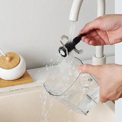 Smoothie Maker - Two hands rinse a food chopper's blade assembly and clear plastic container under a running faucet over a sink