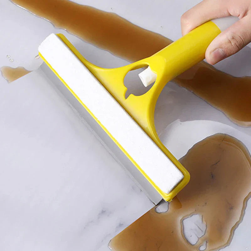 Window Squeegee Cleaner - Hand holding a yellow and white squeegee scraping brown liquid off a smooth light-colored surface
