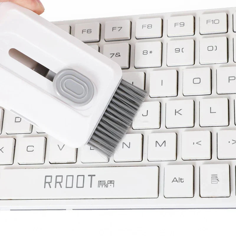 Car Cleaning Brush Kit - Hand holds the cleaning tool with extended brush, brushing debris from gaps between white keyboard keys.