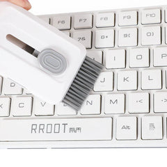 Car Cleaning Brush Kit - Hand holds the cleaning tool with extended brush, brushing debris from gaps between white keyboard keys.